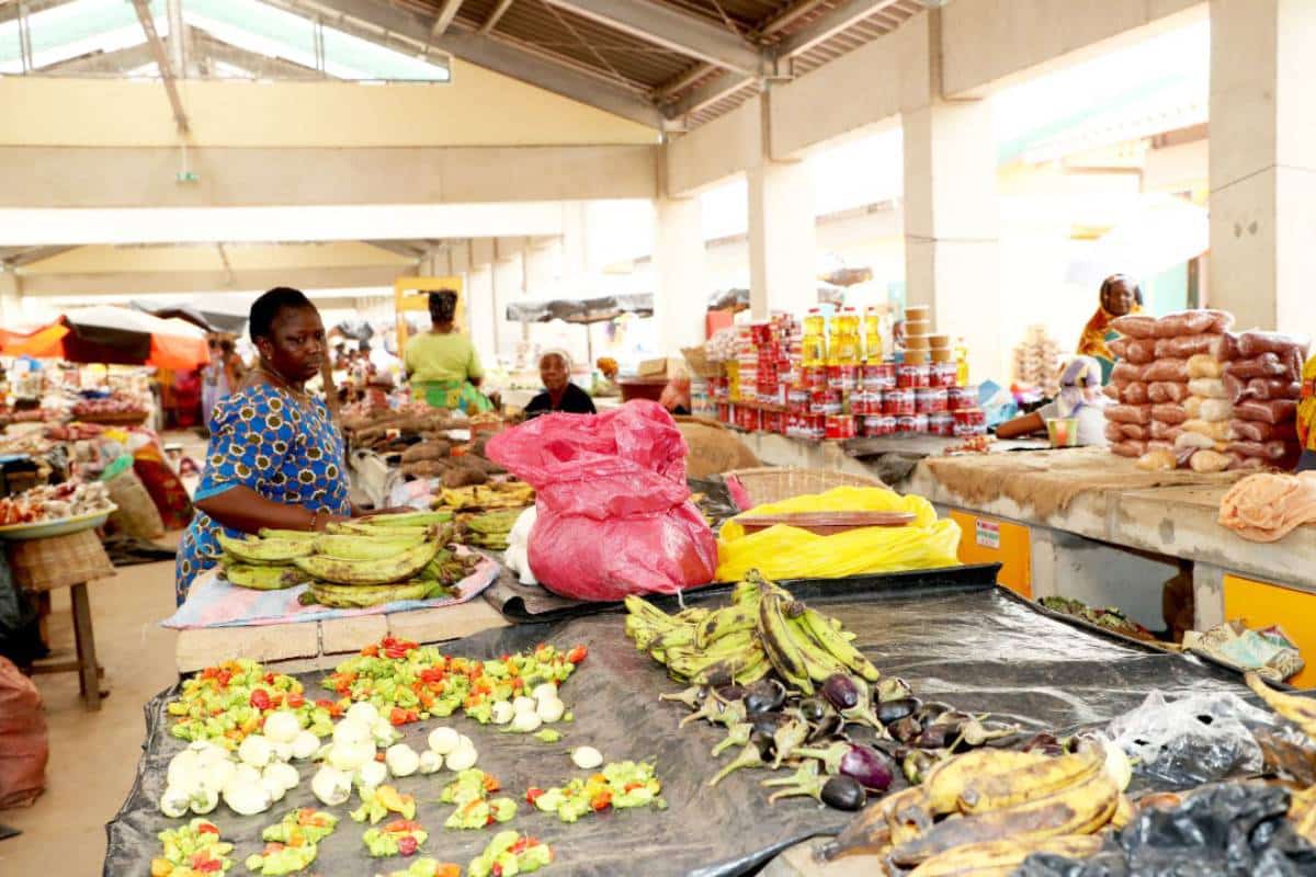 Coût de la vie en Côte d'Ivoire : étal de légumes et de bananes plantain sur un marché couvert
